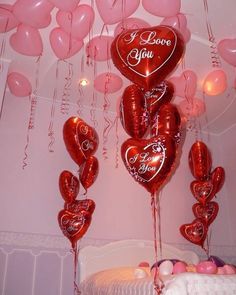 heart shaped balloons with the words i love you on them hanging from a ceiling in a bedroom