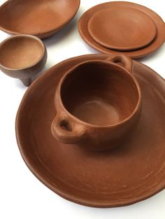 three brown bowls and two plates on a white surface