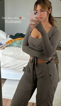 a woman taking a selfie with her cell phone in front of her face and wearing brown pants