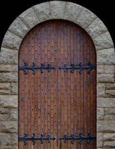 an arched wooden door with iron bars on it