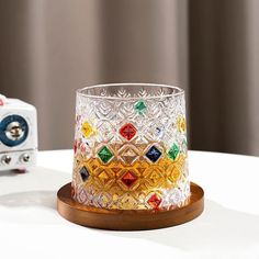 a glass candle holder sitting on top of a white table next to a small clock