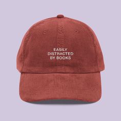 Calling all bookworms! The Easily Distracted by Books Corduroy Cap is the perfect accessory for anyone who'd rather be lost in a novel than doing just about anything else. Whether you're at the bookstore, the library, or just daydreaming about your next read, this cap lets the world know where your mind wanders. 🎨 For the Book Obsessed Featuring the charming Easily Distracted by Books embroidery, this cap is a must-have for literature lovers. The vintage-inspired corduroy fabric adds a cozy, cl Book Hat, Books Embroidery, Corduroy Cap, Funny Hats, Easily Distracted, Gifts For Bookworms, Corduroy Fabric, Wiener Dog, Mode Inspiration