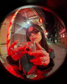 a woman taking a selfie with her camera in front of a building at night