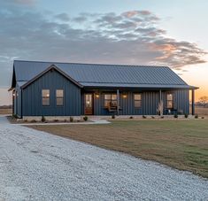 a blue house sitting on top of a grass covered field next to a gravel road