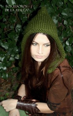 a woman with long hair wearing a green hat and holding a pair of brown gloves