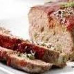 sliced meatloaf on a white plate with garnish and seasoning sprinkles