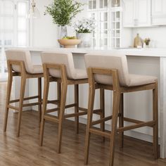 three beige bar stools sitting in front of a kitchen island