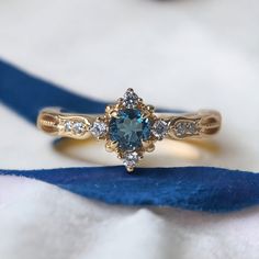 a blue and white diamond ring sitting on top of a blue ribbon