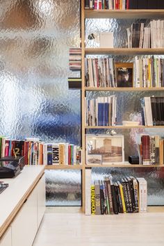 a bookshelf filled with lots of books next to a wall covered in metallic foil