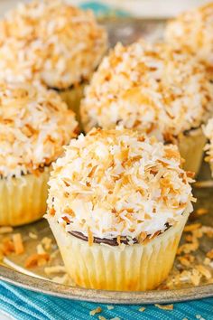 several cupcakes with coconut toppings on a plate