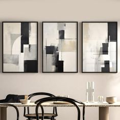 three paintings hang on the wall above a dining room table with chairs and a vase