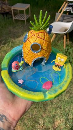 a hand holding a toy in the shape of a pineapple on top of a pool