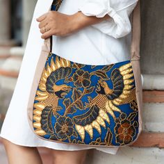 Sawunggaling refers to a traditional Javanese pattern inspired by the King's favorite rooster, a symbol of the nation's power and beauty. Featured in many complexes, this captivating image is now present in Wahyu Sulistiani's cotton shoulder bag, crafted using batik techniques. The accessory comes in a blue hue, with golden-toned plastic beads adding an elegant touch. On top of that, the design has a zippered closure, a black cotton lining and an interior pocket. Unique Pottery, Buy Bead, Plastic Beads, Blue Hues, Handbag Accessories, Black Cotton, Batik, Rooster, Premium Quality