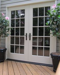 two potted plants sitting on top of a wooden deck next to a patio door