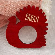 a red wooden brooch with the name sarah on it and a white background