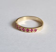 Handmade delicate 14k gold half eternity ring, stoned with 7 beautiful red Rubies.  This Gold Ruby ring is beautiful alone or stacked together with other rings and is colorful and pretty on your finger.  The price is for one ring. Materials: The red Ruby band ring is available in nickel free, 14 karat gold plating over a brass or silver base.  Can be also ordered in solid sterling silver, 9k or 14k solid gold.  A perfect engagement ring or just a beautiful gift for you. Dimensions: The ring widt Ruby Stackable Round Band Promise Rings, Yellow Gold Ruby Eternity Band As Gift, Red 14k Gold Stackable Birthstone Rings, Red Half Eternity Band As A Gift, Classic Red Eternity Band As A Gift, Minimalist Yellow Gold Ring With Ruby, Ruby Half Eternity Band Gift, 14k Gold Fine Jewelry Stackable Ruby Ring, Stackable 14k Gold Ruby Ring For Promise