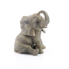 an elephant figurine sitting on the ground with it's trunk in its mouth