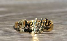 The Debbie: Ladies 14K Yellow Gold Debbie Name Ring. Crafted in 14 karat yellow gold, this trendy name ring displays the name Debbie. The perfect gift for the lady who has everything. Currently a finger size 5.75, this ring can be resized for an additional charge. Each piece has been hand selected and meticulously identified and graded by a Graduate Gemologist who has been awarded a degree by the Gemological Institute of America (GIA). Please visit our Shop's About Page or our website for more i Classic Gold Engraved Ring With Custom Name, Elegant Formal Ring Engraved With Name, Elegant Gold Nameplate Engraved Ring, Elegant Gold Engraved Nameplate Ring, Classic Gold Rings With Custom Name, Gold Engraved Name Ring For Promise, Elegant Engraved Nameplate Ring With Names, 14k Gold Engraved Name Ring, Gold Nameplate Ring With Custom Name