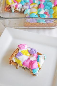 a white plate topped with a slice of cake covered in marshmallows next to a casserole dish