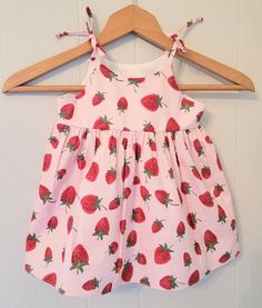 This fun and summery strawberry sundress with matching bloomers for babies and toddlers features a full skirt and shoulder ties that tie into a bow. The bodice is lined with soft cotton and there are no exposed seams on the bodice sides for a more comfortable fit. Fabrics are woven cotton and are machine washable in cool water with like colors and can be machine dried on a low setting. This dress would be great to wear to a Strawberry themed party or event or for everyday wear and play. Sizing i Playful Summer Dress With Tie Straps, Cute Sundress With Tie Straps For Garden Party, Cotton Bubble Romper For Spring Garden Party, Cute Summer Bubble Romper For Garden Party, Spring Garden Party Cotton Bubble Romper, Cute Cotton Dresses With Tie Straps, Summer Beach Dress With Strawberry Print, Cute Cotton Dress With Tie Straps, Sweet Summer Beach Dresses