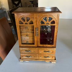 an old wooden cabinet with glass doors on it's front and side drawers, sitting on a table