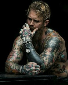 a man with tattoos and piercings on his arms