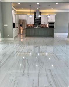 an empty kitchen and living room with white marble flooring in the middle of it