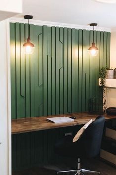 an office with green paneling and two lamps hanging from the ceiling over a desk