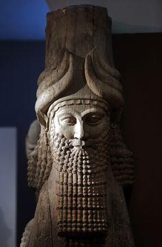 an ancient statue with a beard and long horns on it's head is displayed in a museum