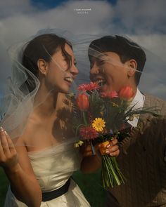 a bride and groom holding flowers under their veil