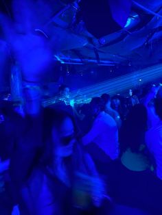 a group of people dancing in a dark room with blue lighting on the walls and floor