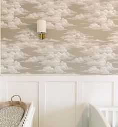 a baby's crib in front of a wall with clouds on it