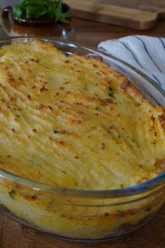 a casserole dish with cheese and herbs in it sitting on a table next to a napkin