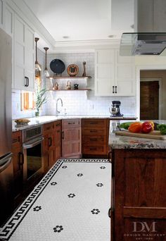 a kitchen with wooden cabinets and stainless steel appliances, along with a purple rug on the floor