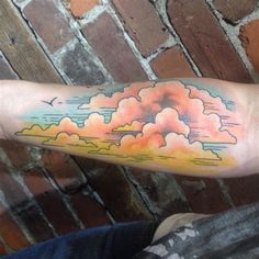 a person with a colorful cloud tattoo on their arm