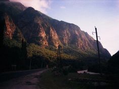 there is a mountain behind the road and telephone poles on the side of the road