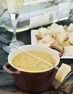 there is a bowl of soup on the table next to crackers and wine glasses