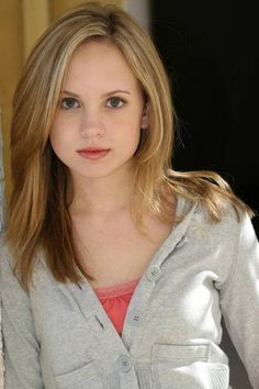 a beautiful young woman leaning against a wall