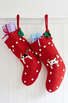 two red christmas stockings hanging on a white wall with polka dot designs and dogs painted on them