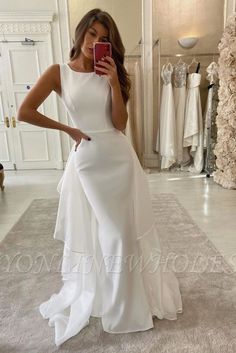 a woman in a white dress taking a selfie with her cell phone and looking at the camera