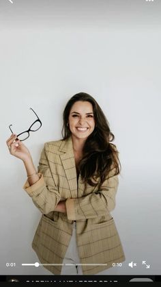 a woman holding up her glasses and smiling