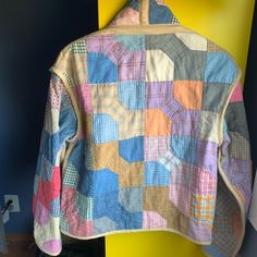 a multicolored jacket hanging up against a yellow and blue wall in a room