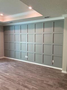 an empty room with wood floors and gray garage doors on the wall, in front of a fireplace