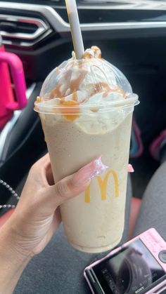 a woman holding up a drink in her hand with a straw sticking out of it