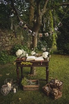 an old table with pictures hanging from it and some flowers on the table next to it