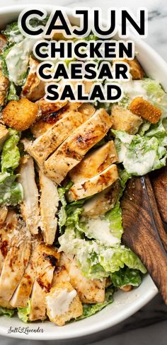 a bowl of salad with serving utensils and test overlay that reads cajun chicken caesar salad Cajun Caesar Salad, Ceasar Salad With Chicken Recipe, Spicy Ceaser Dressing, Cajun Chicken Caesar Salad, Chicken Seasoning For Caesar Salad, Blackened Chicken Caesar Salad, Best Chicken Caesar Salad Recipe, Cajun Chicken Salad Recipe