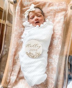 a baby wrapped in a white blanket is laying on its side and smiling at the camera