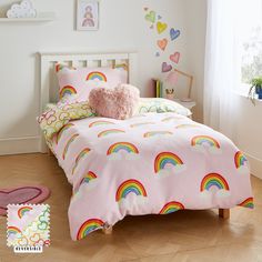 a child's bed with pink sheets and rainbows on it