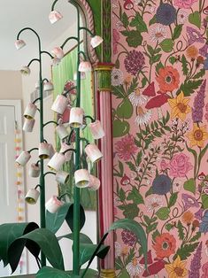 a room with pink and green wallpaper, potted plant and mirror