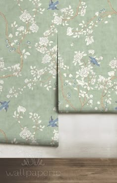 two blue birds sitting on top of a green flowered wallpaper covered in white flowers